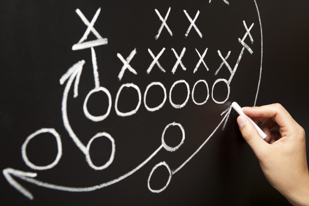 Hand drawing a game strategy with white chalk on a blackboard.