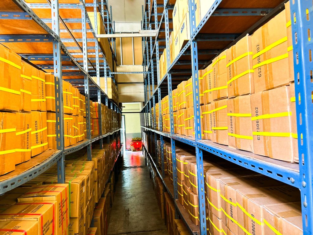 Rak gudang dengan penataan stok barang yang terorganisir.